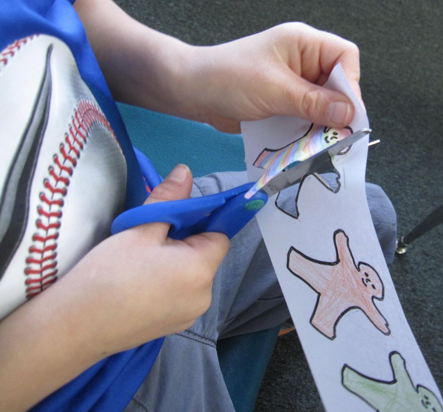 Person cutting out paper figures with scissors.