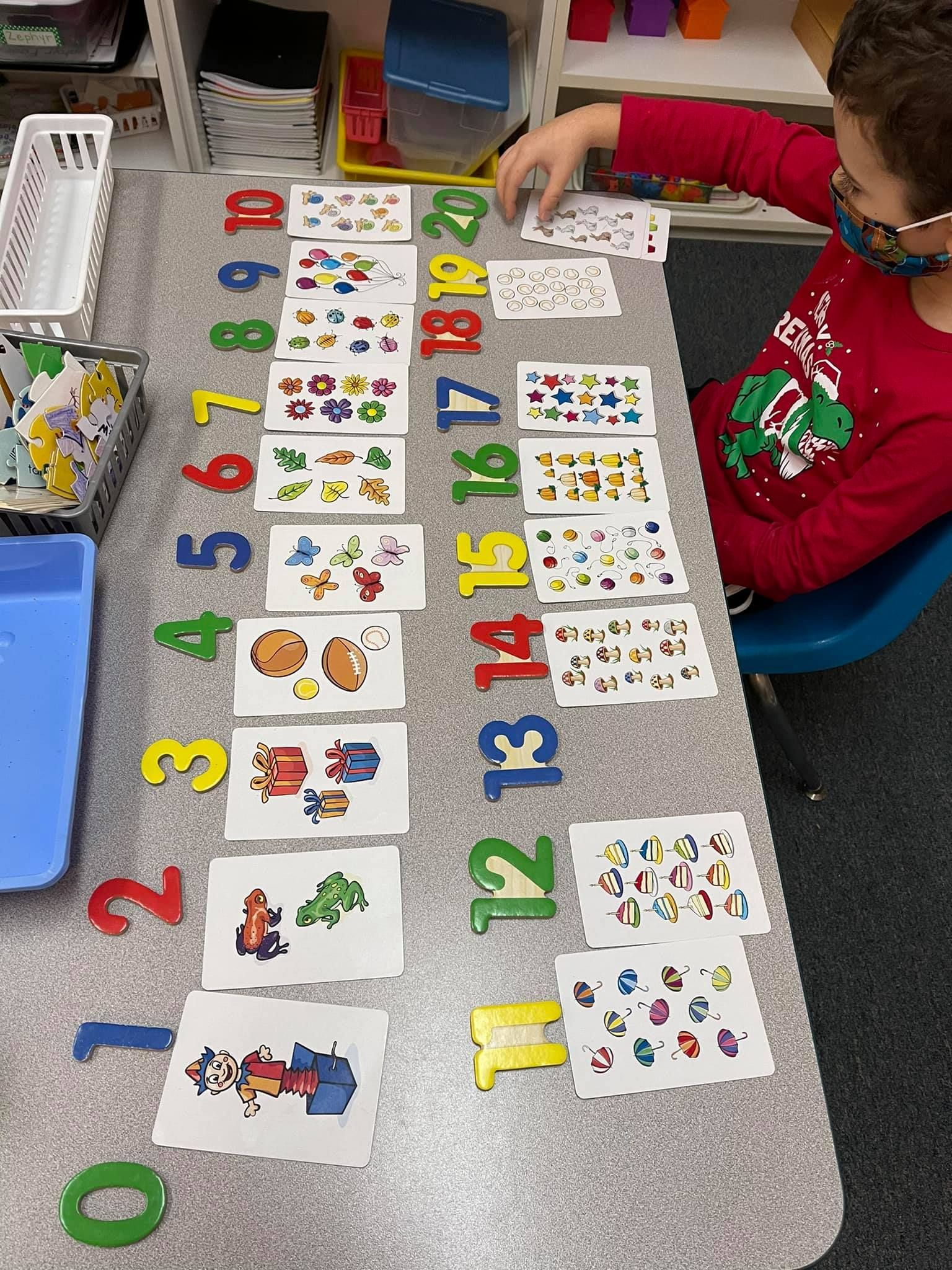 Child arranging number cards and quantities on a table, learning to count