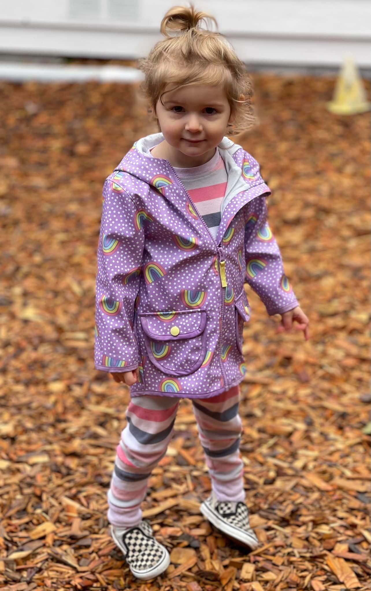 Young girl in purple raincoat with rainbows