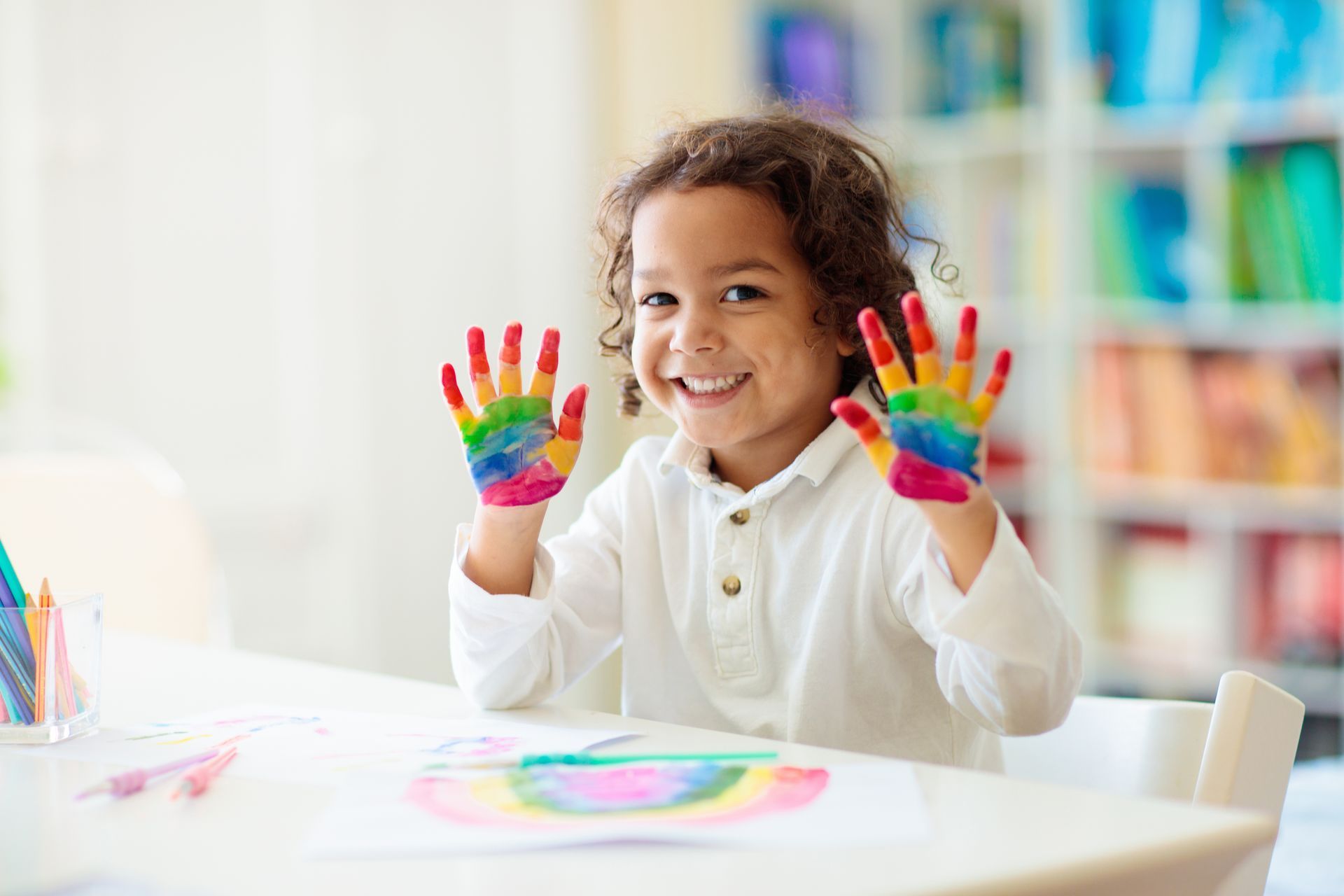 Young child with painted hands smiles