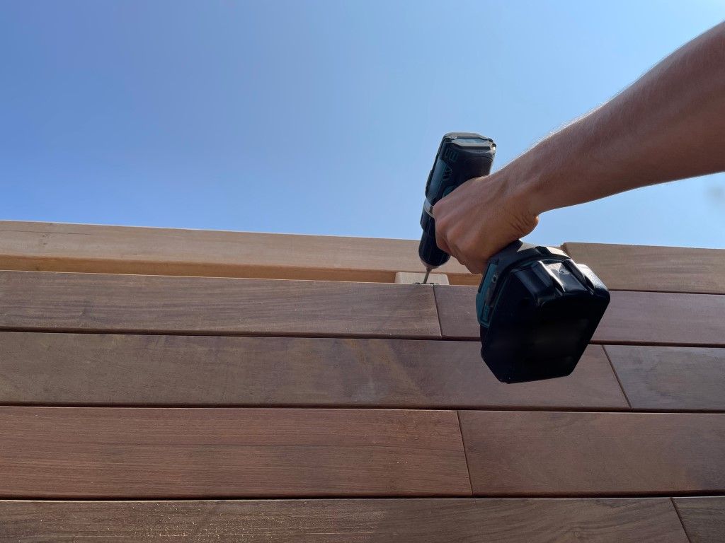 person installing engineered wood siding with a drill 