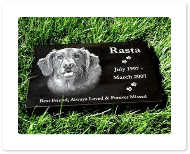 Black pet memorial plaque on grass with dog portrait and the name Rasta