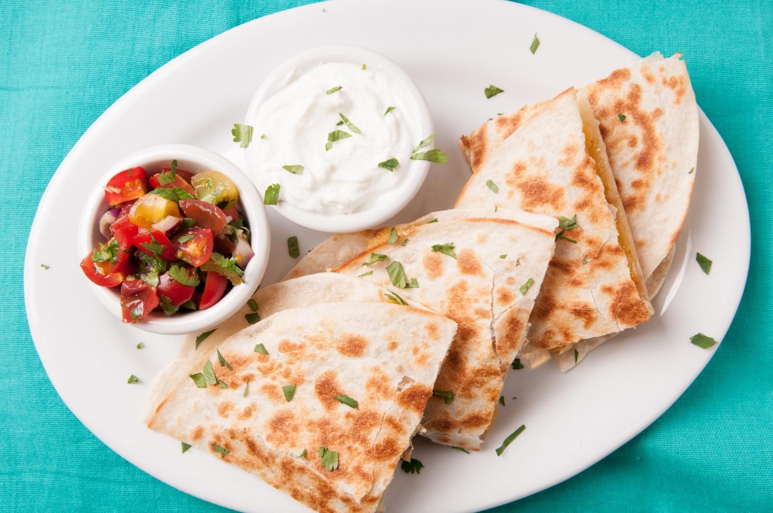 Quesadilla wedges with salsa and sour cream on a white plate