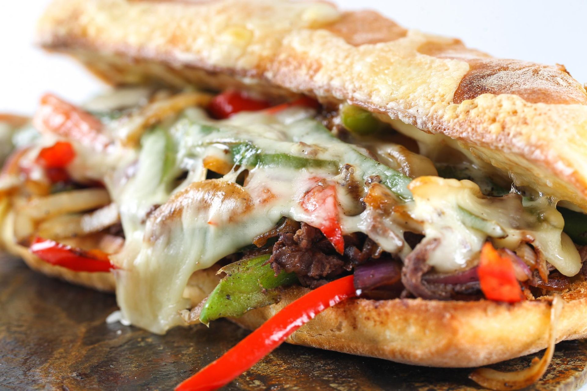 Grilled sandwich with melted cheese, roasted peppers, and greens on crusty bread