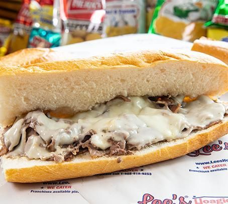 Large cheesesteak sandwich on a tray with melted cheese on a soft roll