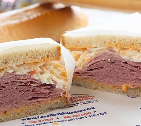 Close-up of a stacked roast beef sandwich on a paper tray, showing layers of meat and coleslaw