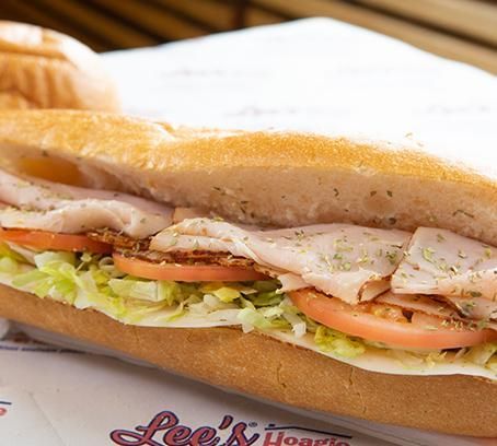Sub sandwich with turkey, lettuce, and tomato on a tray with Lee's Hoagie House logo