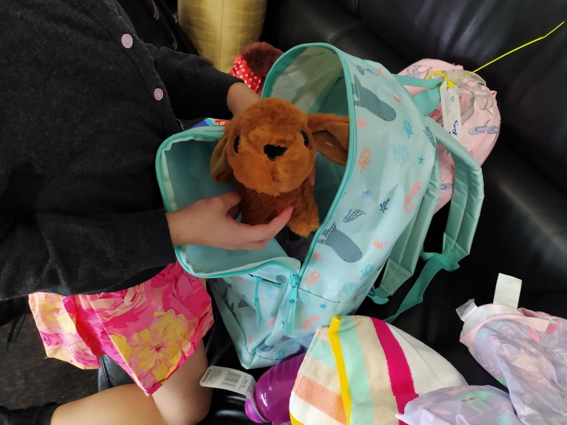 A child is putting a stuffed toy in a backpack