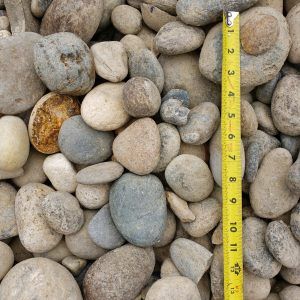 Pile of smooth gray and tan pebbles with a yellow measuring tape standing upright beside them