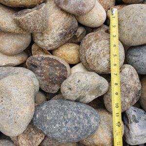 Close-up of assorted rounded stones with a yellow measuring tape for scale