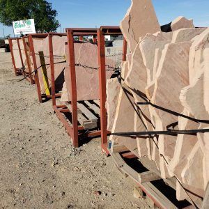 Large tan rock slabs strapped to metal pallets in an outdoor yard