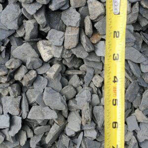 Gray gravel stones beside a yellow measuring tape showing size markings