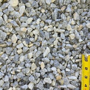 Close-up of gray gravel stones with a yellow measuring tape along the right edge