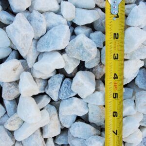 White and gray gravel stones beside a yellow measuring tape in close-up.
