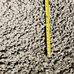 Yellow measuring tape in a bed of small light-gray gravel or stones.