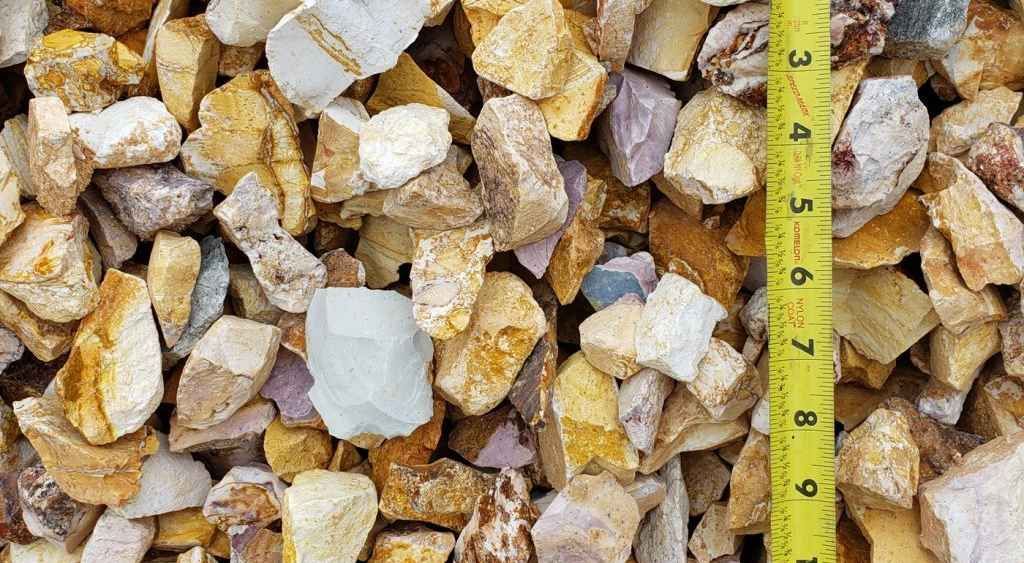 Pile of white and tan rocks or mineral chunks with a yellow measuring tape on the right edge