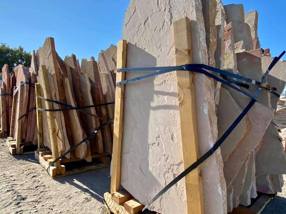 Large slabs of stone bound with straps and stacked outdoors in a quarry yard