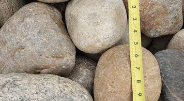 Close-up of large gray and tan rocks with a yellow measuring tape stretched vertically between them