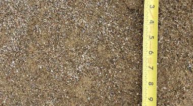 Gravel surface with a yellow measuring tape laid vertically along the right side.