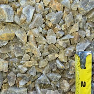 Close-up of tan crushed gravel with a yellow measuring tape at the lower right.