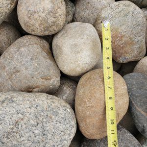 Assorted smooth rocks with a yellow measuring tape showing their size
