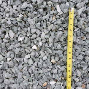 Gray gravel stones beside a yellow measuring tape showing size scale