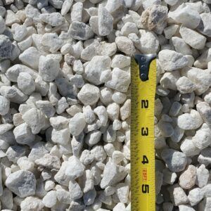 White gravel stones with a yellow measuring tape showing size scale.