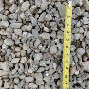 Gray gravel stones with a yellow measuring tape showing scale in inches.