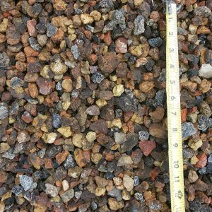 Close-up of multicolored gravel stones beside a measuring tape for scale