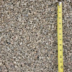 Close-up of small gravel stones next to a yellow measuring tape showing size.