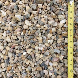 Close-up of mixed gravel stones with a yellow measuring tape along the right edge
