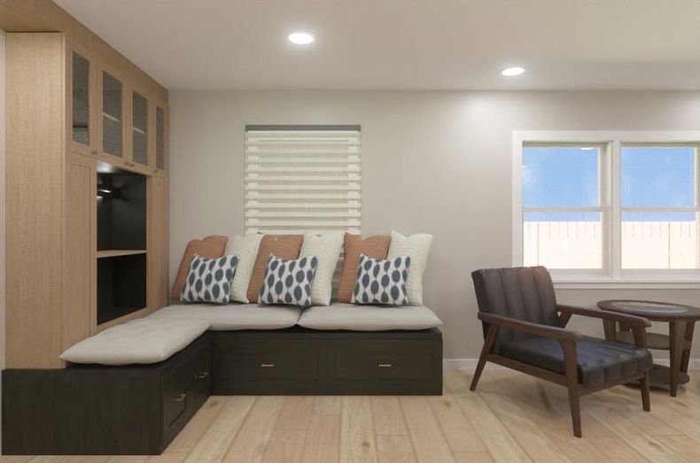 Modern living room with sectional sofa, patterned pillows, wood shelving, and dining table by a window.