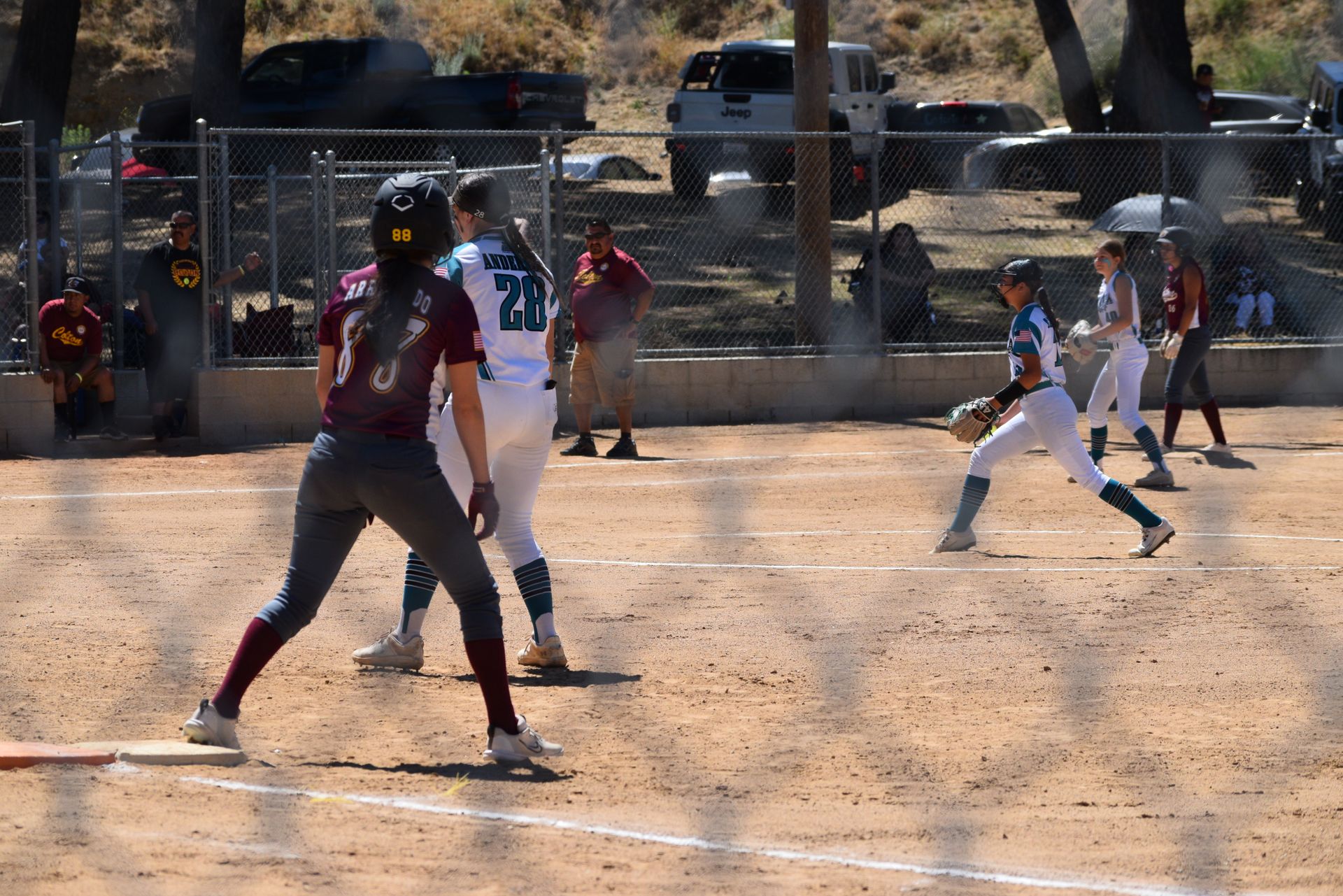 Baseball player sliding into base as another player attempts to catch the ball.
