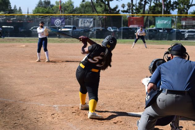 Baseball player sliding into home plate, catcher in front. Blue and gold uniforms, action shot.