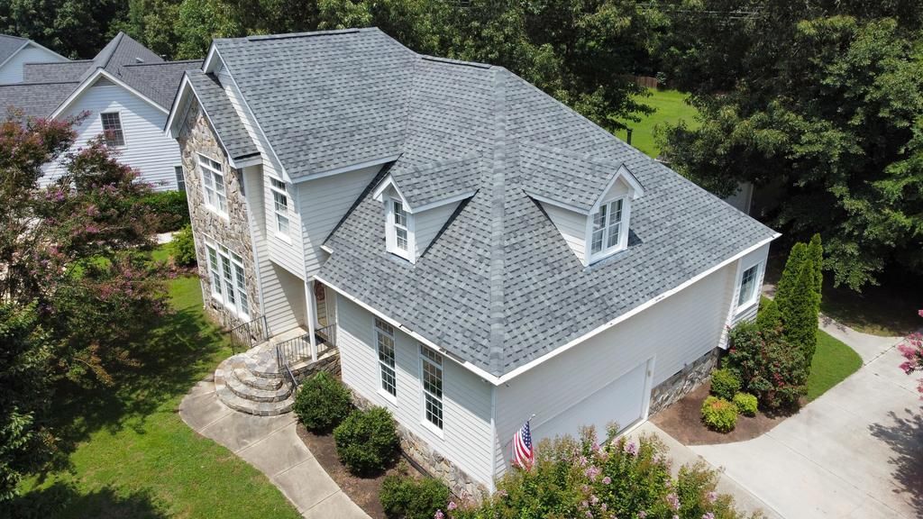 An aerial view of a large white house with a gray roof.