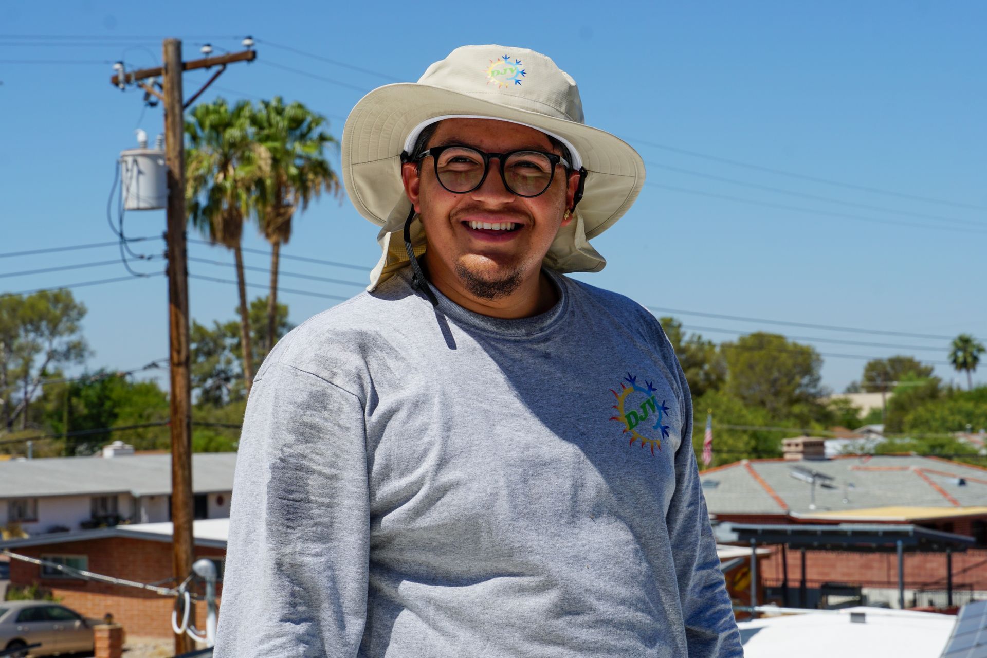 A man wearing a hat and glasses is smiling for the camera.