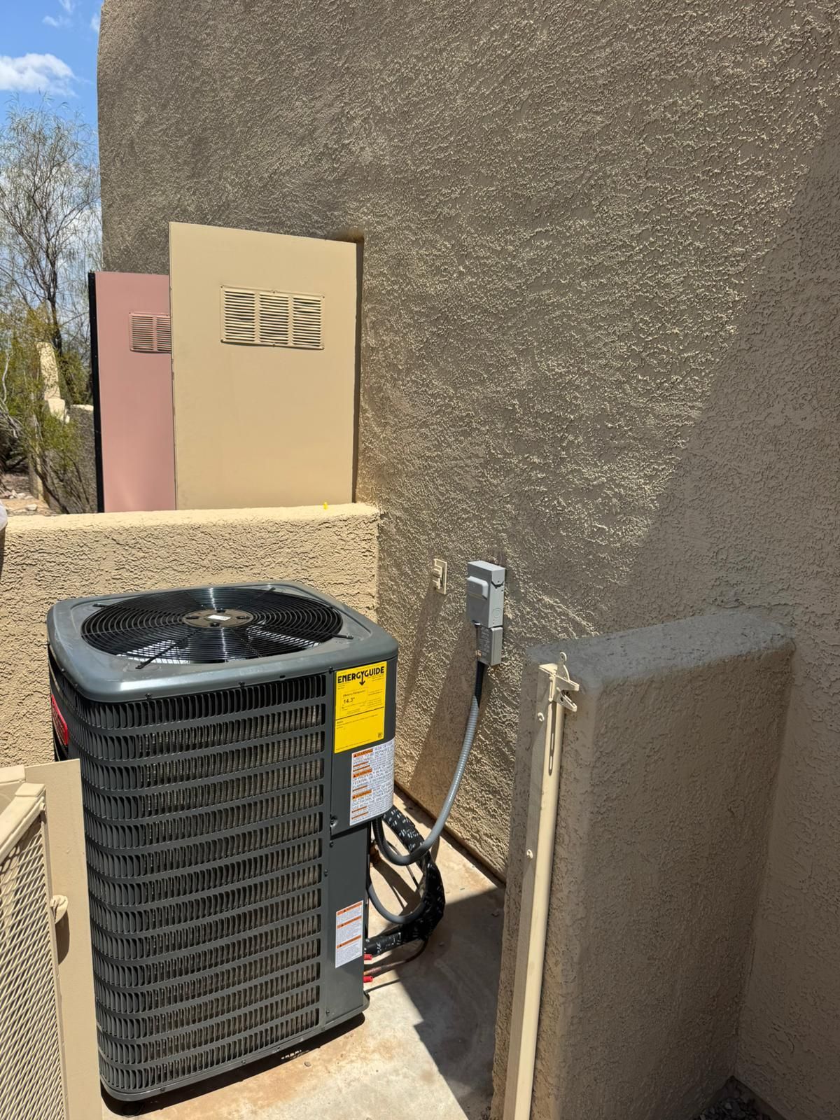 An air conditioner is sitting outside of a building next to a wall.