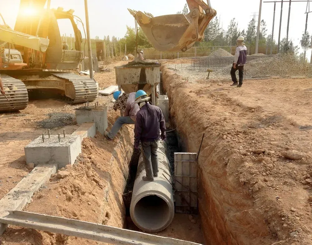 Construction Workers Install a Large Concrete Pipe in a Dirt Trench — Copp & Co Civil Plant Hire in Proserpine, QLD