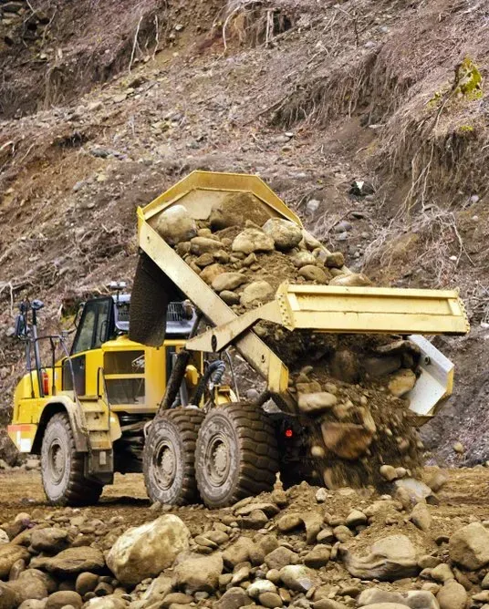 A Yellow Dump Truck Actively Tipping a Heavy Load of Rocks and Dirt — Copp & Co Civil Plant Hire in Proserpine, QLD