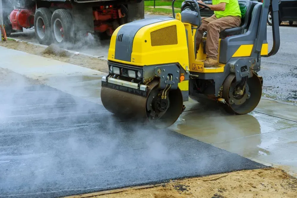 A Worker Operates a Yellow Industrial Road Roller to Compact Fresh — Copp & Co Civil Plant Hire in Airlie Beach, QLD