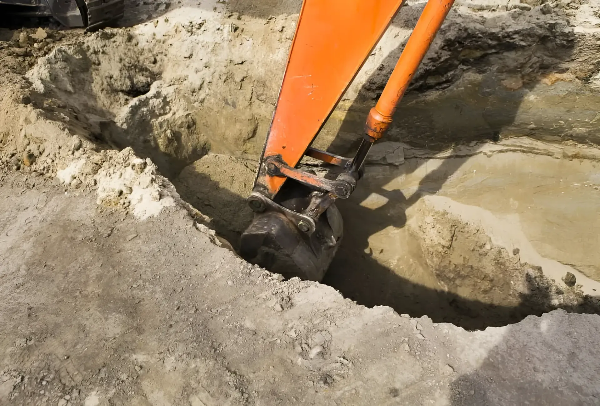 An Orange Excavator Bucket Digs Into a Patch of Excavated Dirt and Gravel — Copp & Co Civil Plant Hire in Mount Julian, QLD