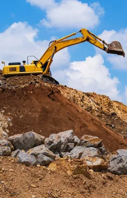 A Yellow Excavator Sits Atop a Dirt and Rock Pile Under a Bright Blue Sky — Copp & Co Civil Plant Hire in Cannonvale, QLD
