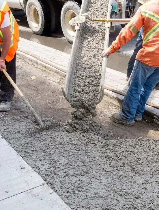 Two Construction Workers in High-visibility Vests Pour Wet Concrete — Copp & Co Civil Plant Hire in Bowen, QLD
