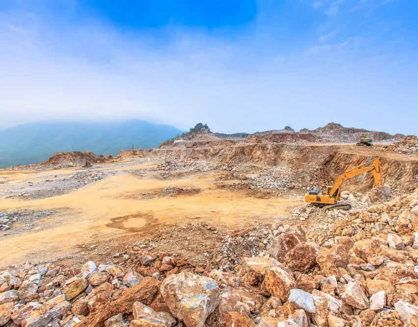 A Yellow Excavator Sits in a Vast, Rocky Quarry With a Sandy Ground — Copp & Co Civil Plant Hire in Airlie Beach, QLD