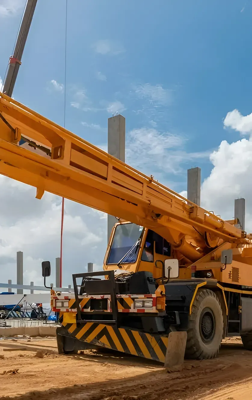 A Yellow Mobile Crane Parked on a Construction Site With Concrete Pillars — Copp & Co Civil Plant Hire in Proserpine, QLD