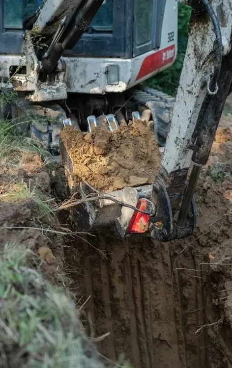 A White Bobcat Excavator Digs a Trench in the Dirt — Copp & Co Civil Plant Hire in Airlie Beach, QLD