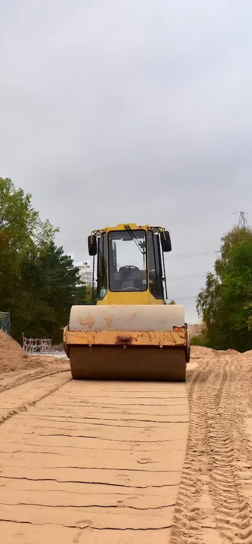 A Yellow Road Roller Travels Forward on a Dirt Path Under a Cloudy Sky — Copp & Co Civil Plant Hire in Mount Julian, QLD