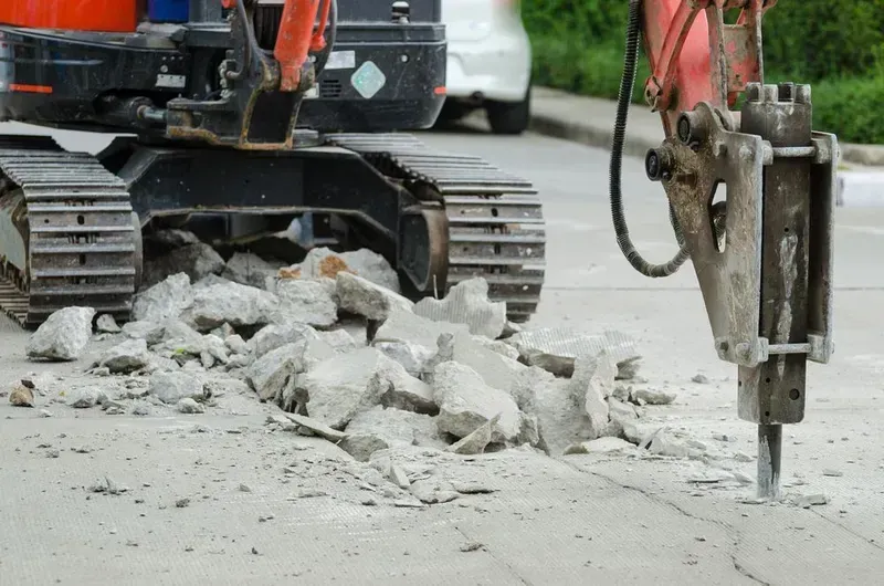 An Orange Construction Excavator Uses a Hydraulic Hammer Attachment — Copp & Co Civil Plant Hire in Bowen, QLD