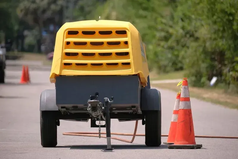 A Yellow Portable Air Compressor Trailer Parked on an Asphalt Road — Copp & Co Civil Plant Hire in Airlie Beach, QLD