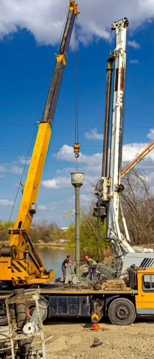 A Yellow Crane and a White Drill Rig Operate on a Construction — Copp & Co Civil Plant Hire in Cannonvale, QLD